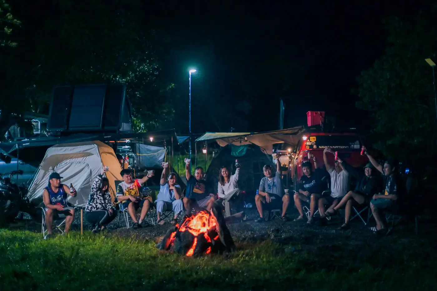 Guests raising a toast around a bonfire at the Amor Adventures basecamp at night